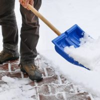 avoid an insurance claim - man clearing sidewalk after snow