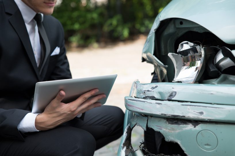 insurance claim adjuster with tablet examining damaged car ruhl automotive insurance adjuster