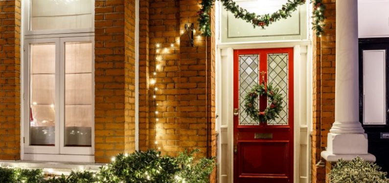 front of a home decorated for christmas