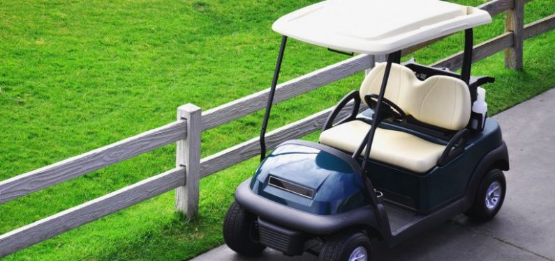 golf cart parked next to a fence