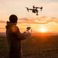 man operating a drone at sunset