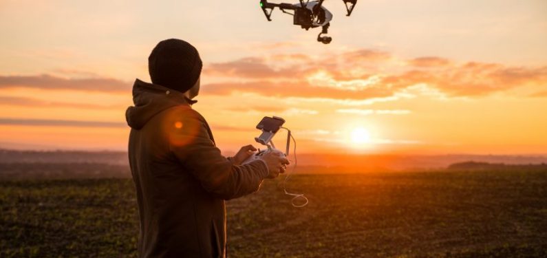 man operating a drone at sunset