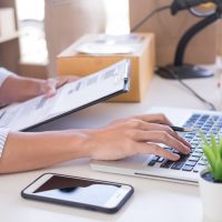 man with inventory list on a clipboard and laptop