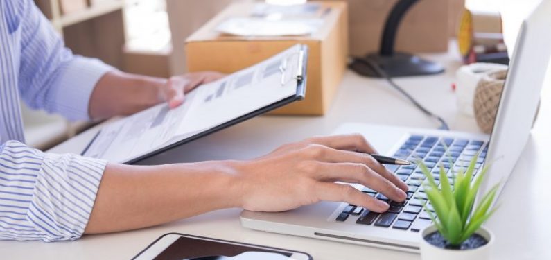 man with inventory list on a clipboard and laptop