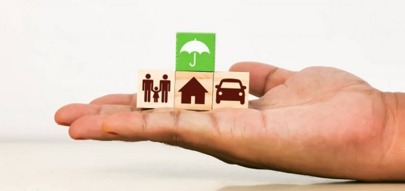 insurance concept hand holding blocks with umbrella, house, car, and family icons