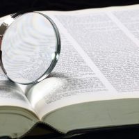open dictionary with magnifying glass on top