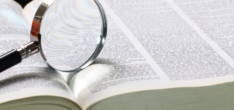 open dictionary with magnifying glass on top